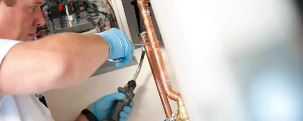 Water heater repair technician testing copper pipe connections and controls in Allentown, PA